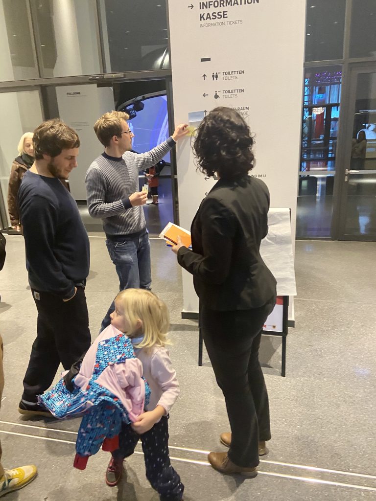 Workshop participants using post it notes to adjust public space signage while a small child wanders past