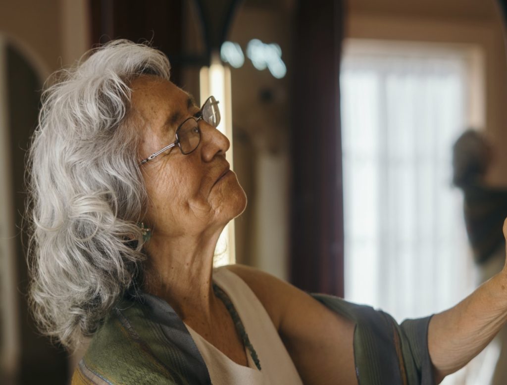 Older adult woman looking at picture on wall