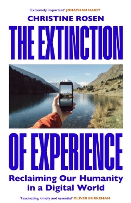 Front cover of The Extinction Of Experience - a person taking a photo of a mountain lake and the phone showing the image of the lake 